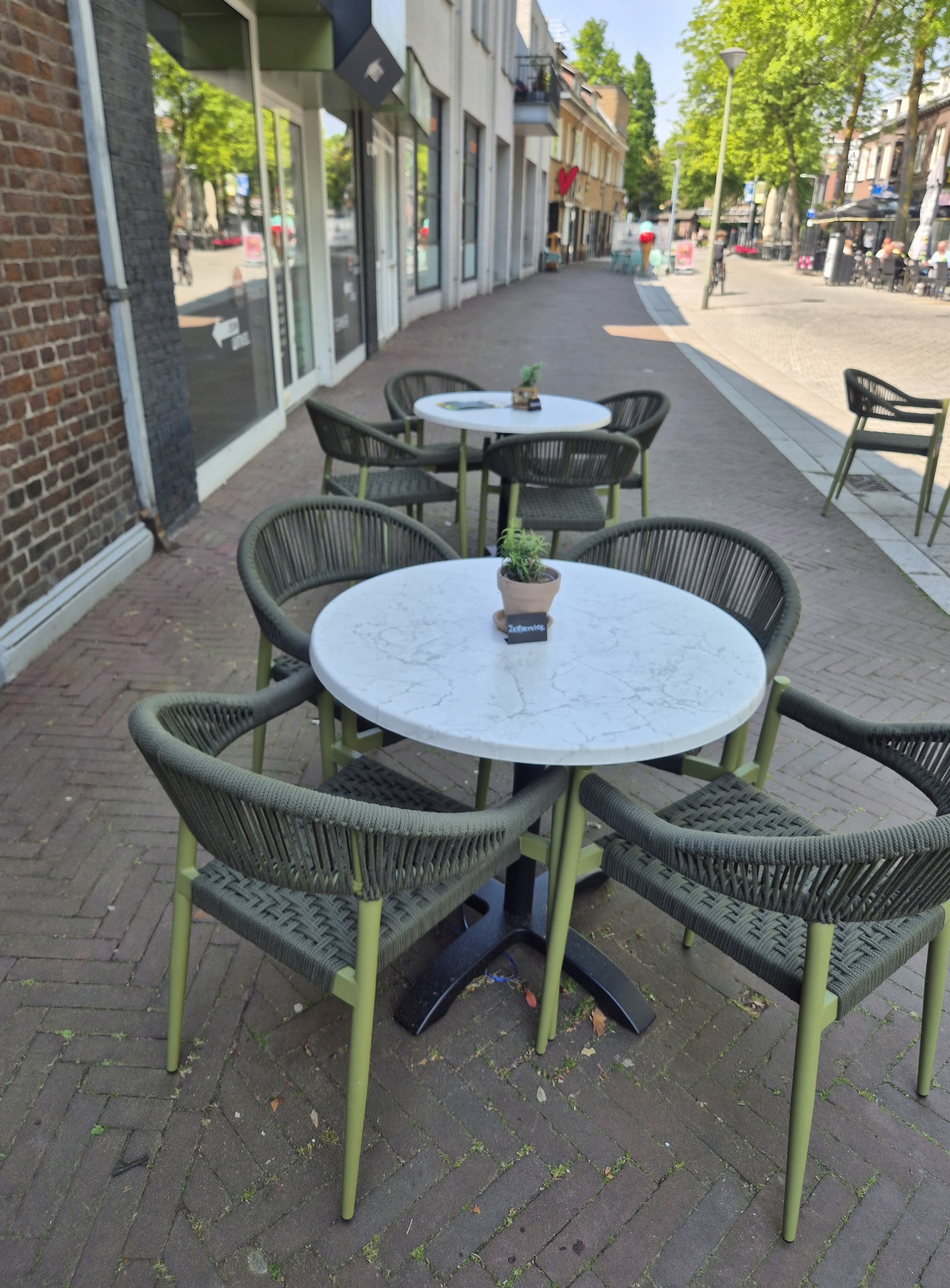 Het terras van Bij Nadia met ronde tafeltjes aan de Markt in Panningen
